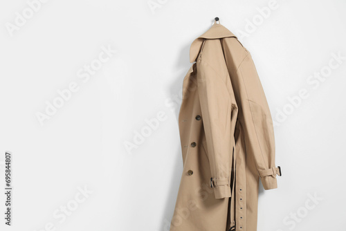 Photos Beige trench coat hanging on hook rack on white wall, space for text