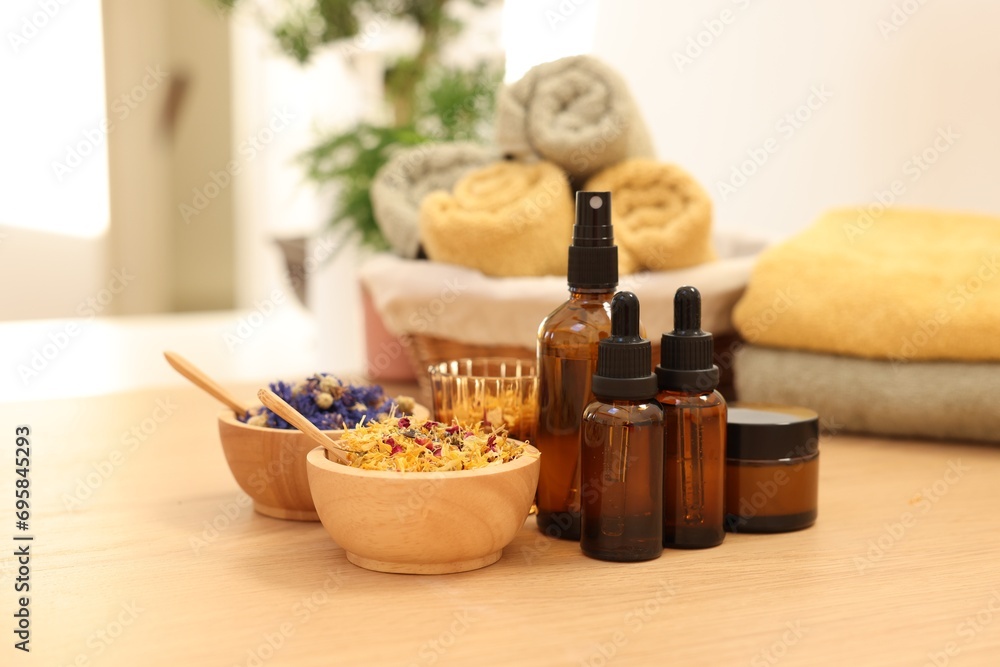 Dry flowers, bottles of essential oils and jar with cream on wooden table indoors. Spa time Dry flowers, bottles of essential oils and jar with cream on wooden table indoors. Spa time