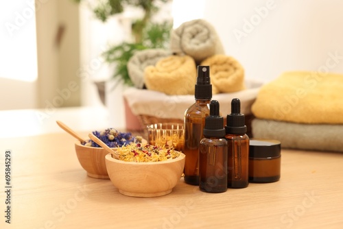 Dry flowers  bottles of essential oils and jar with cream on wooden table indoors. Spa time