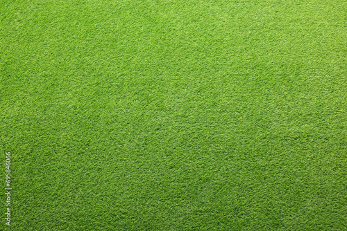 Green artificial grass as background, top view photo