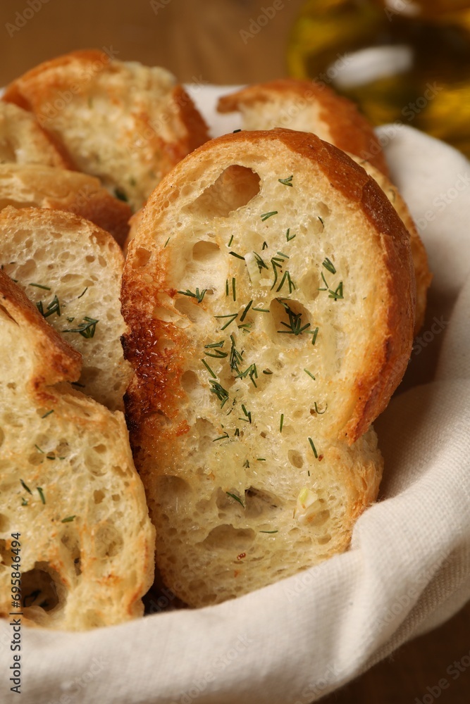 Tasty baguette with garlic and dill in basket, closeup