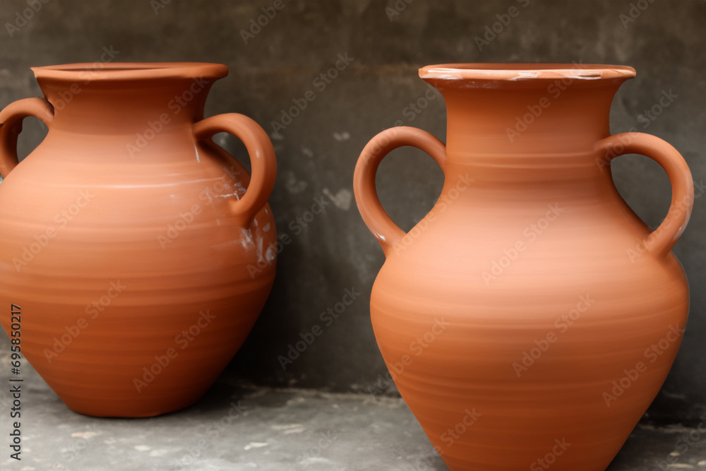 clay art. large orange handmade clay vases stand on a dark stele background, creative concept