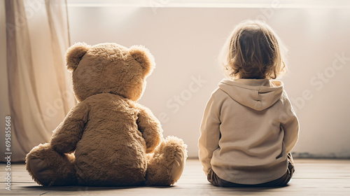 Rear view of a cute baby sitting next to his plush