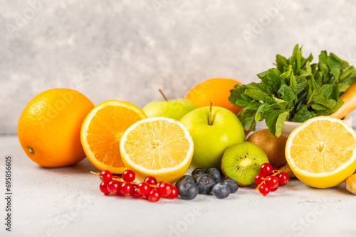Oranges  apples  lemons  kiwi  mint  red currants and blueberries on a textured cement background. Fruits and berries. Vitamins for immunity. Place for text. Copy space.