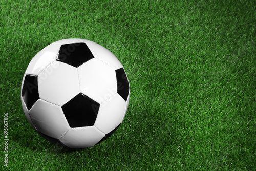 One soccer ball on green grass, space for text. Sports equipment