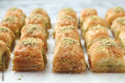 Delicious fresh baklava with chopped nuts on white table, closeup. Eastern sweets