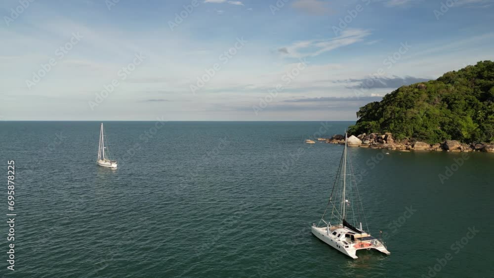 Aerial shot of boat and yacht cruising near a rocky island with crystal clear water Aerial shot of boat and yacht cruising near a rocky island with crystal clear water