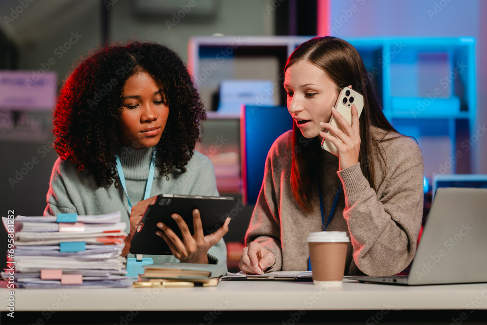 African American trainee with an afro and a Caucasian colleague working together in an office, possibly during overtime. African American trainee with an afro and a Caucasian colleague working together in an office, possibly during overtime.