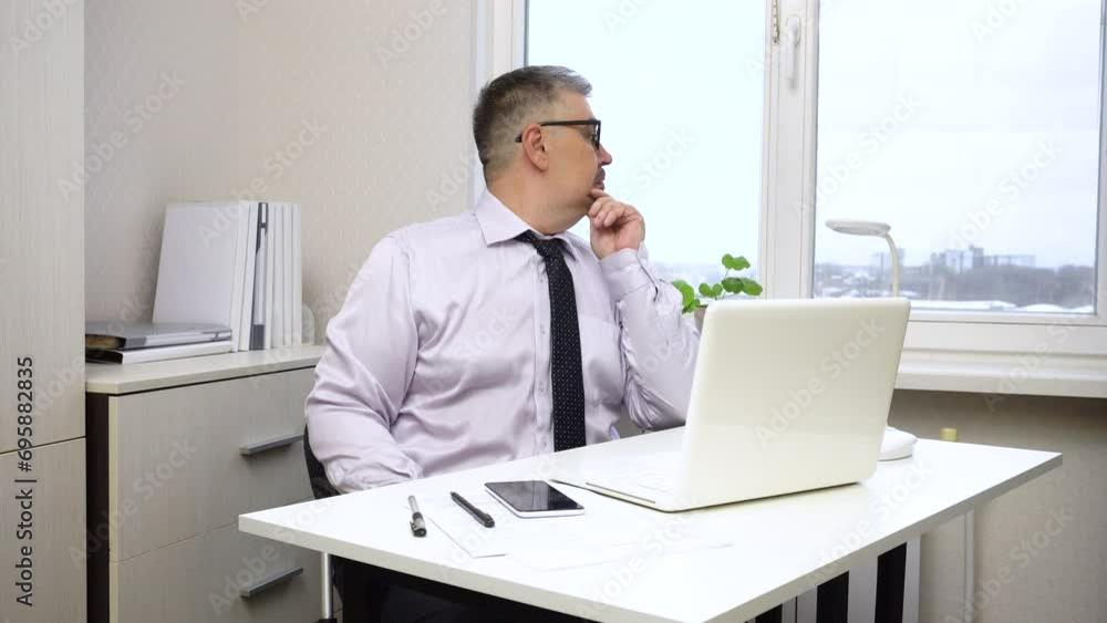 A man works at a computer. He looks at the monitor and thinks. The video is suitable for content about office work, entrepreneurship, overcoming crises and problems, and decision-making strategies. A man works at a computer. He looks at the monitor and thinks. The video is suitable for content about office work, entrepreneurship, overcoming crises and problems, and decision-making strategies.