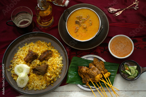Muslim food including beef biryani, masala curry, beef satay is placed on the table, view from above