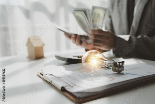 A real estate agent sits in his office, A business owner is counting money and making notes in a financial book, The financier is verifying the income received from the client's investment,