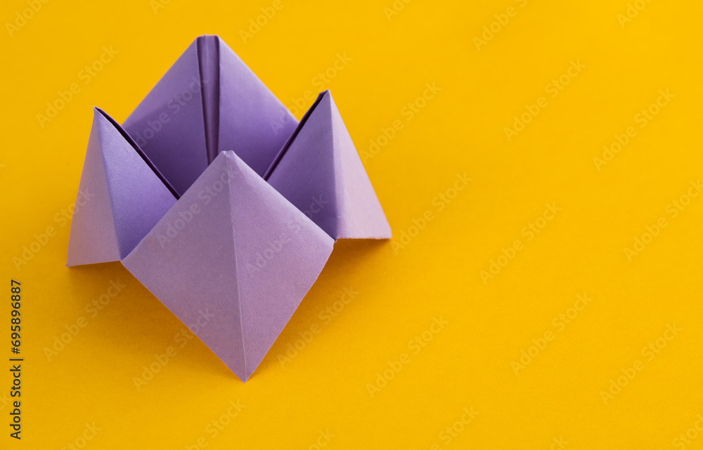 Origami paper fortune on yellow background Origami paper fortune on yellow background