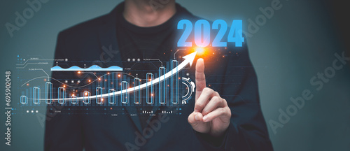 2024 Step into the world of finance and economics with a businessman's virtual screen analysis of investment trends in 2024. Explore the stock market's potential for growth and profit photo