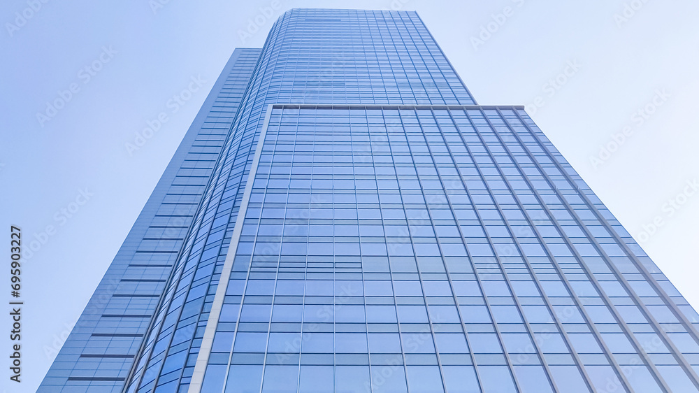 Low angle view of modern office building with glass window and clear blue sky background for business and finance concept. Low angle view of modern office building with glass window and clear blue sky background for business and finance concept.