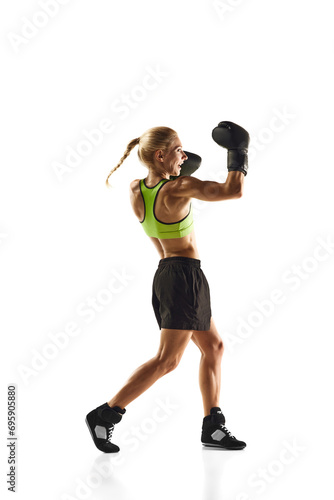 Fototapeta Naklejka Na Ścianę i Meble -  Upper cut punch. Young woman with muscular fit body training, boxing athlete practicing isolated on white background. Concept of sport, active and healthy lifestyle, strength and endurance, body care