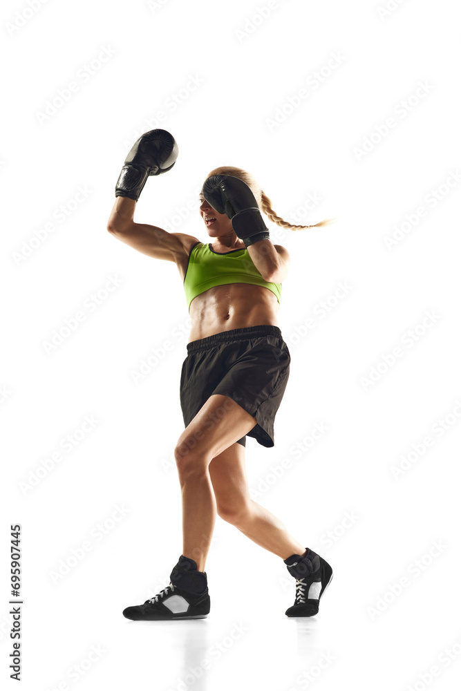 Muscular young woman, boxing athlete practicing, punching, training isolated over white background. Concept of sport, active and healthy lifestyle, strength and endurance, body care