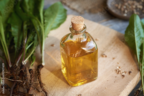 A bottle of dandelion root tincture with fresh plant