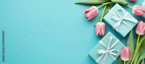 A bouquet of pink tulips and a gift box on a blue background. Spring greeting for birthday, Easter or Mother's day. #695909640