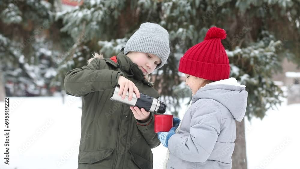 Happy little smiling girl and teen boy standing outdoor in a winter season and drinking cocoa. Holiday concept Happy little smiling girl and teen boy standing outdoor in a winter season and drinking cocoa. Holiday concept