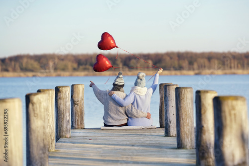 verliebtes Paar am See mit roten Herzballons photo