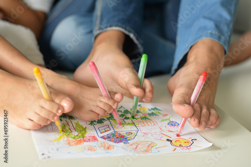 The family holds their pencils with their feet and draws 