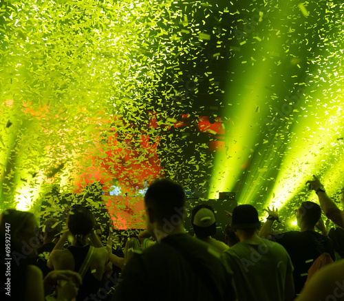 Crowd of people attending a musical performance. Yellow confetti falling down on excited audience