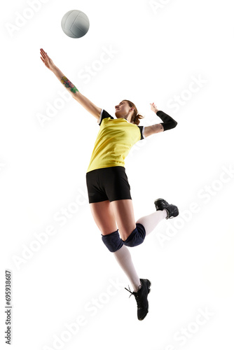 Full-length dynamic image of young woman, volleyball player in motion, practicing, hitting ball in jump isolated over white background. Concept of sport, competition, active, healthy lifestyle, hobby