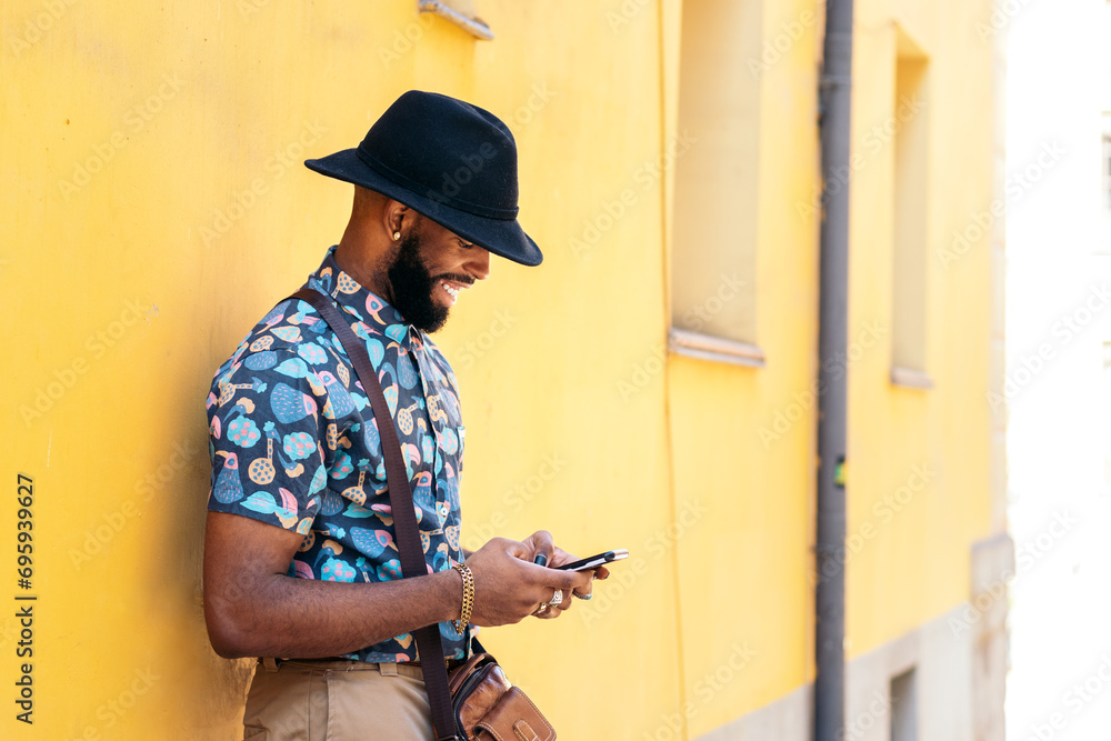 Stylish black man using smartphone outdoors over yellow background Stylish black man using smartphone outdoors over yellow background