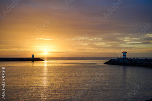 Pier of the harbour of Scheveningen, The Hague during the sunset. On the background a new horizon with windmills.