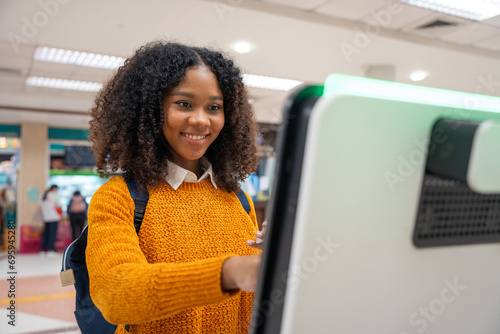 Black women with short, curly hair check-in via automatic machines by themselves in the airport to travel or study abroad.	 photo