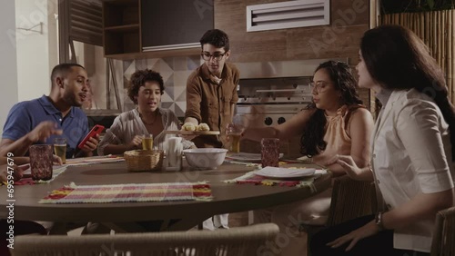 Jovem servindo seus convidados, na cozinha de sua casa. Cinematico 4k. photo
