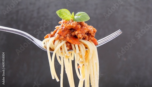 spaghetti with sauce bolognese hanging on a fork on or white background