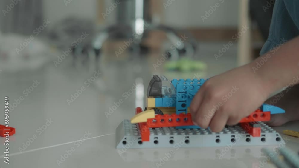 Adorable Asian boy, about 3-6 years old playing with miniature blocks as a toy windmill and having various toy accessories happily placed on the table inside his home, white background. Adorable Asian boy, about 3-6 years old playing with miniature blocks as a toy windmill and having various toy accessories happily placed on the table inside his home, white background.