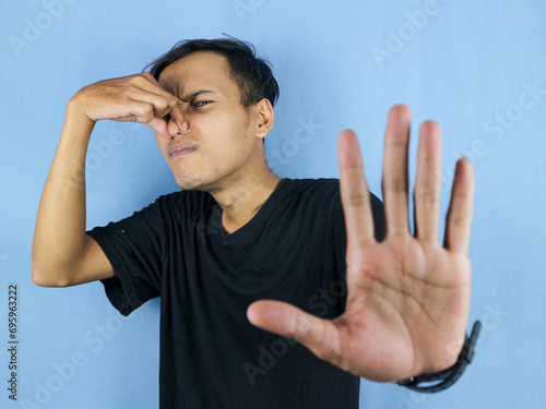 gesture handsome Asian man smelling something stinky and disgusting, intolerable smell photo