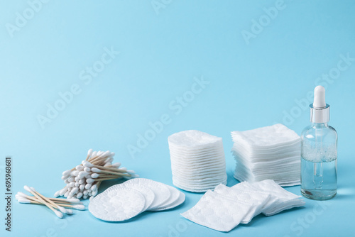 Bamboo eco-friendly cotton swabs and cotton pads and a glass bottle with a dropper with essence or serum on a blue background. Copy space. Skin care, personal hygiene