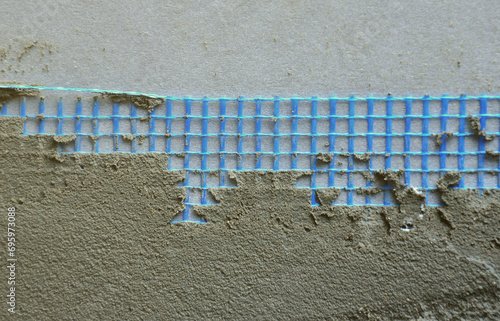 Fototapeta Naklejka Na Ścianę i Meble -  The texture of the wall, covered with gray foam polystyrene plates, covered with a blue reinforcing mesh and covered with a mixture for gluing it. Stage of wall insulation