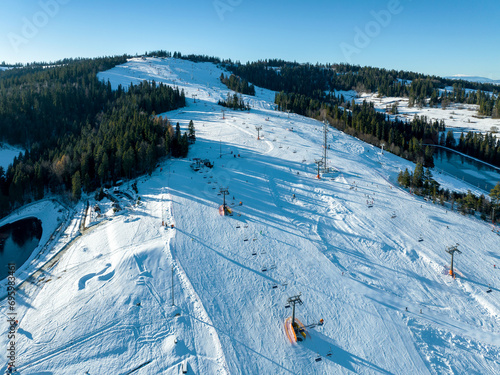 Obraz na płótnie Ski slope, chairlifts, skiers and snowboarders in Bialka Tatrzanska ski resort in Poland on Kotelnica Mountain in winter. Aerial view in low December light w salonie