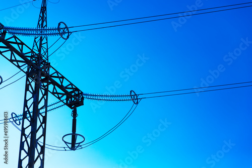 electricity transmission pylon silhouetted against blue sky