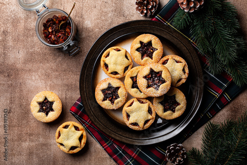 Traditional british christmas Mince pies on a brown plate, sprinkled with sugar. Also called mincemeat or fruit pie, filled with a mixture of fruit, spices and suet. Festive table, directly above.