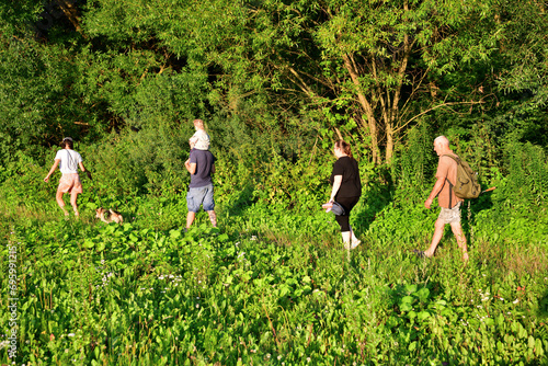 Obraz na płótnie The whole family is walking on a meadow next to the forest on a trip in nature w salonie