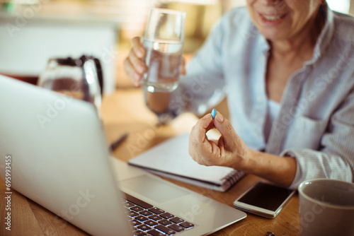 Close up senior woman holding pill with water at home