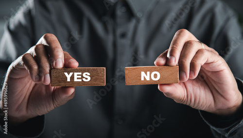 Hands of businessman holding wooden blocks with yes and no words portraying decision-making. Choice symbolizes business success. Think With Yes Or No Choice. photo
