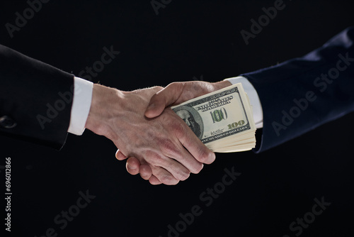 Handshake with the transfer of money on a black background