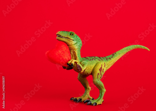Green cute dinosaur with red heart on  red background. Creative minimal greeting card on Valentines day. Love concept.