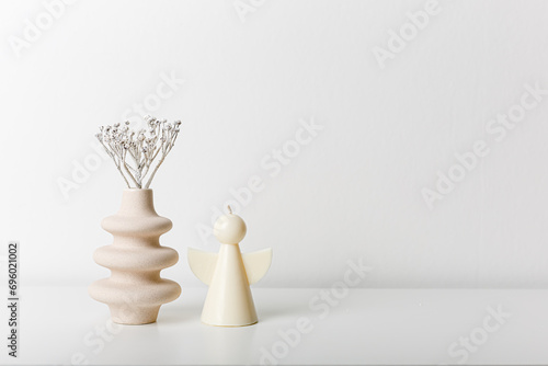 Beige ceramic small vases and candle. Cozy home. Copy space, minimalism, scandinavian decoration. Winter fairy tale. White background. Light wall. Dry garass with snow. photo