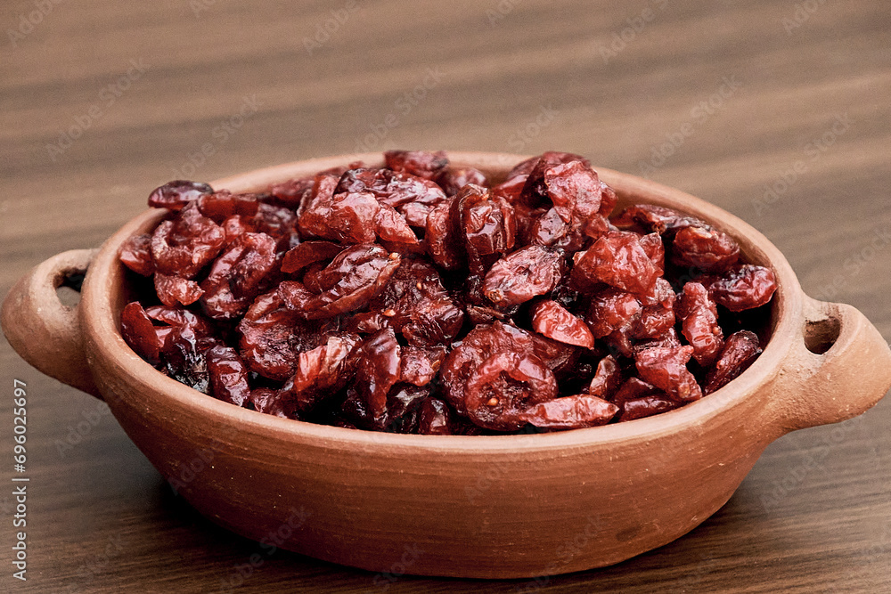 Delicious dried cranberry in a handmade ceramic tank on a brown table Delicious dried cranberry in a handmade ceramic tank on a brown table