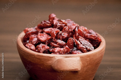 Delicious dried cranberry in a handmade ceramic tank on a brown table