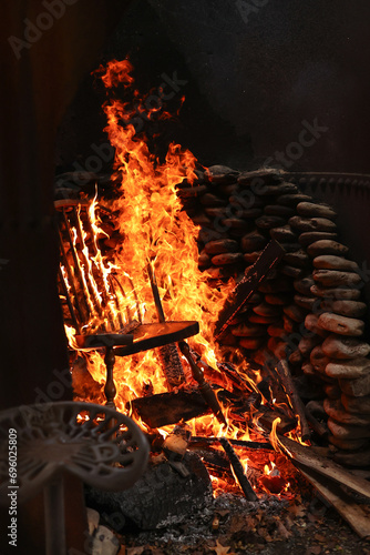 Burning and on fire wooden chair and trash in outdoor burn pit