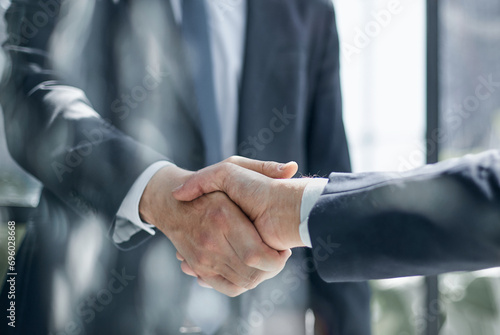 executives shaking hands in front of their manager and a colleague