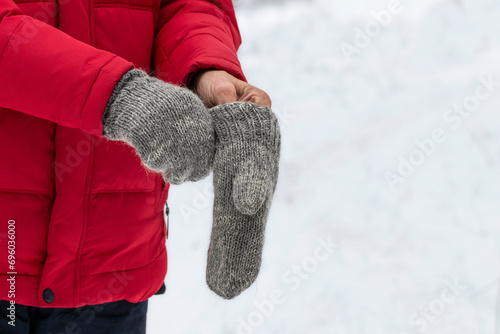 A man puts on knitted mittens on the street in winter.Warm clothes for winter walks. photo
